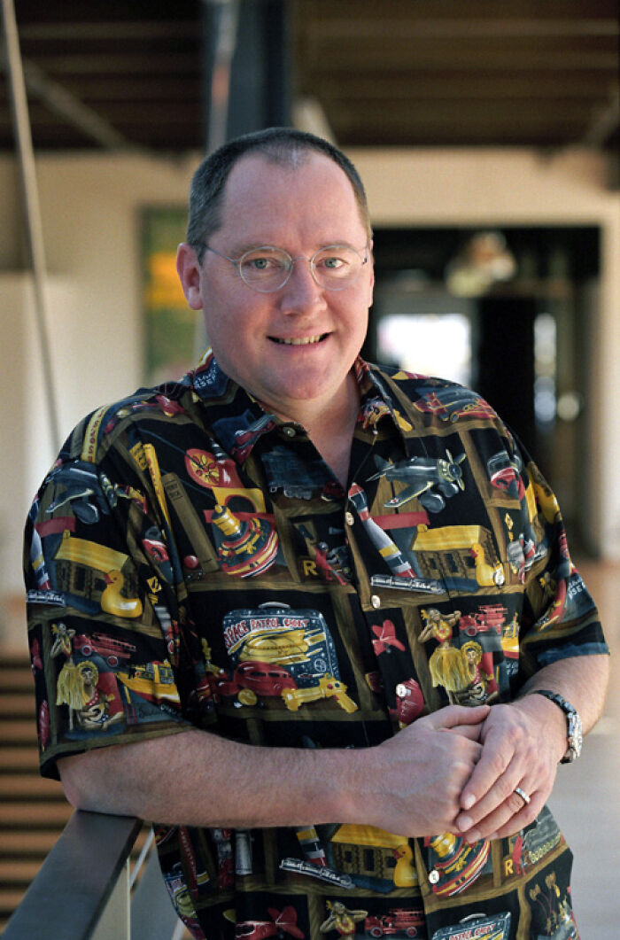 Man wearing glasses and a colorful patterned shirt, smiling while leaning on a railing, reflecting disappointment in idolized people.