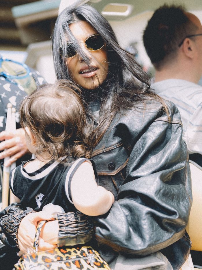 Kourtney Kardashian wearing sunglasses and black leather jacket, holding a child, related to lollipops for women&rsquo;s private parts launch.