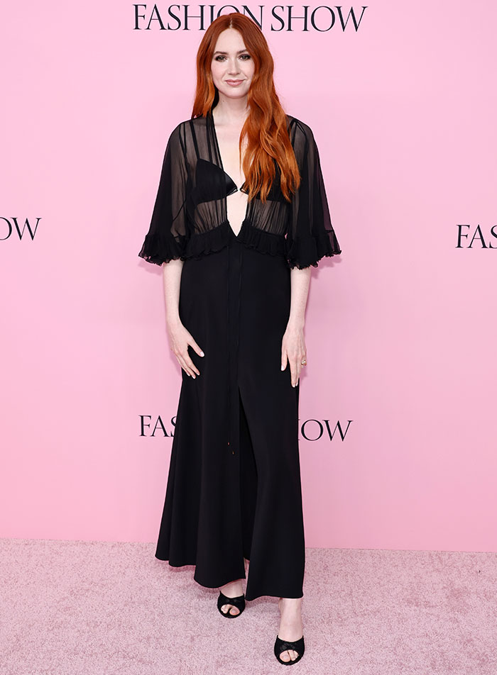 Red-haired woman in a sheer black dress posing at a fashion show, reflecting worst dressed at Victoria's Secret Fashion Show 2025.