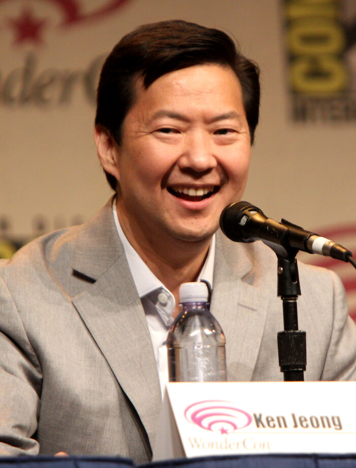 Ken Jeong speaking at a panel, smiling in a gray suit, representing Hollywood stars who found fame after 30.
