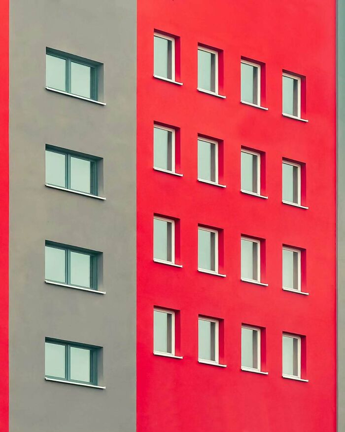 Minimalist architectural design of a building featuring clean lines and contrasting red and gray exterior walls.