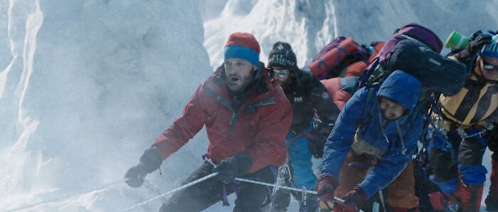 Climbers in cold weather gear ascending an icy mountain, depicting a scene from movies based on true stories.