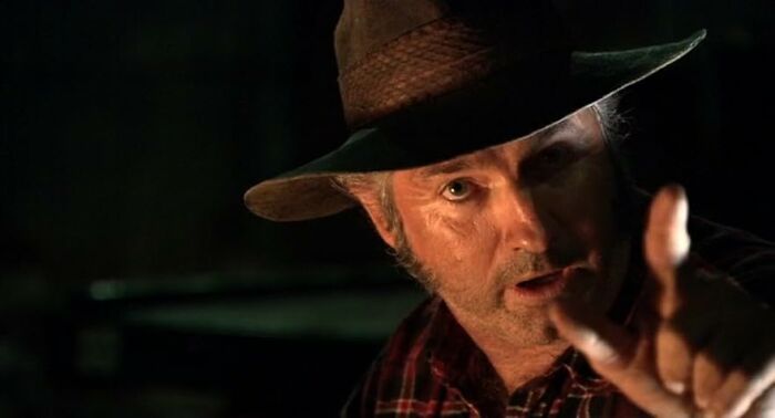Actor in a hat pointing with intense expression in a dramatic scene from movies based on true stories.
