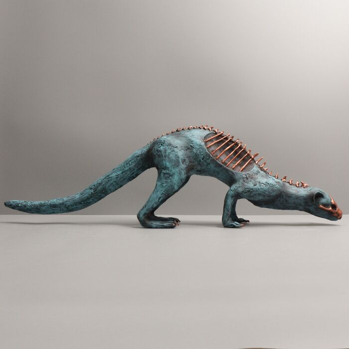Porcelain sculpture of a mythical creature with teal texture and copper spine details resembling relics of forgotten myths.