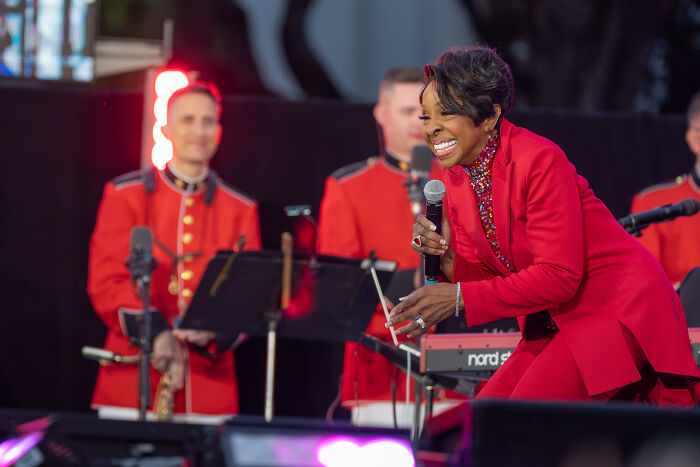 A female celebrity singer in a red suit performing on stage with musicians, highlighting unknown things about celebrities.