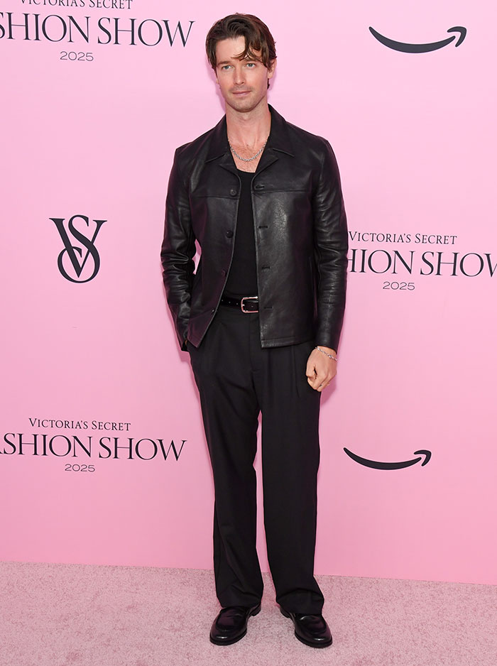 Man in black leather jacket and pants posing on the pink carpet at the Victoria's Secret Fashion Show 2025 worst dressed event.