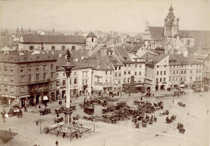 Historic photo showing a bustling city square with horse-drawn carriages in one of the world’s capitals before modern times.