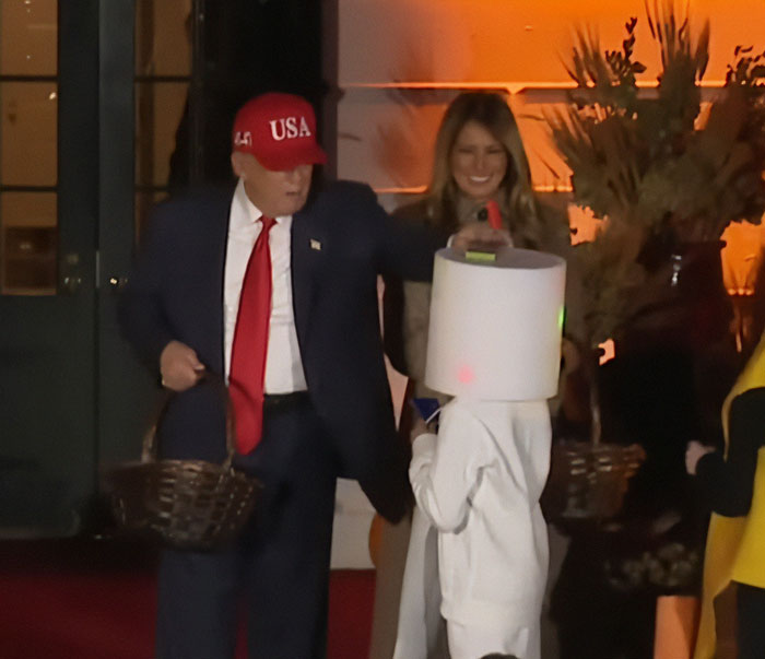 Melania Trump's White House Halloween display with Donald Trump in a red USA hat handing out candy to a child in costume