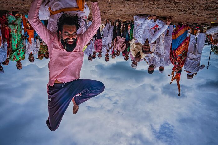 Man jumping joyfully in colorful traditional attire surrounded by a crowd, captured in street photography awards setting.