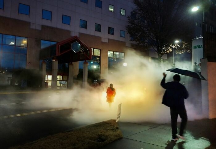 Person walking through street fog at night, capturing the essence of urban life in street photography awards 2025.