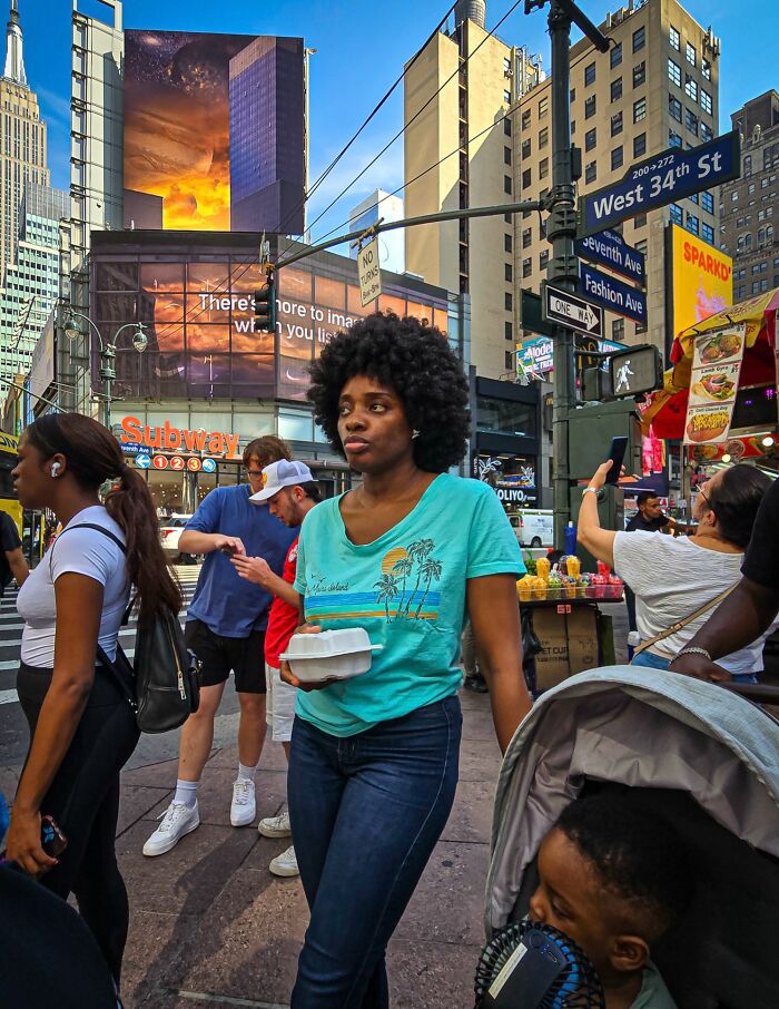 Woman carrying takeout food on busy city street, vibrant scene capturing pure street photography awards spirit.