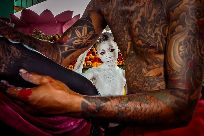 Boy with face paint stands behind heavily tattooed person in vibrant scene, capturing pure street photography spirit.