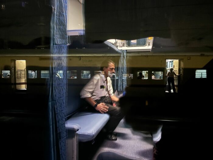 Man sitting inside train carriage with reflections, illustrating street photography capturing urban life moments.