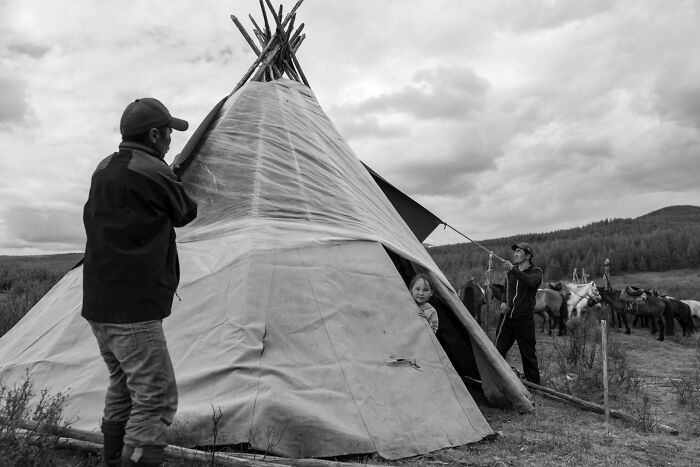 Black and white street photography showing people setting up a traditional tent capturing the soul of the streets.