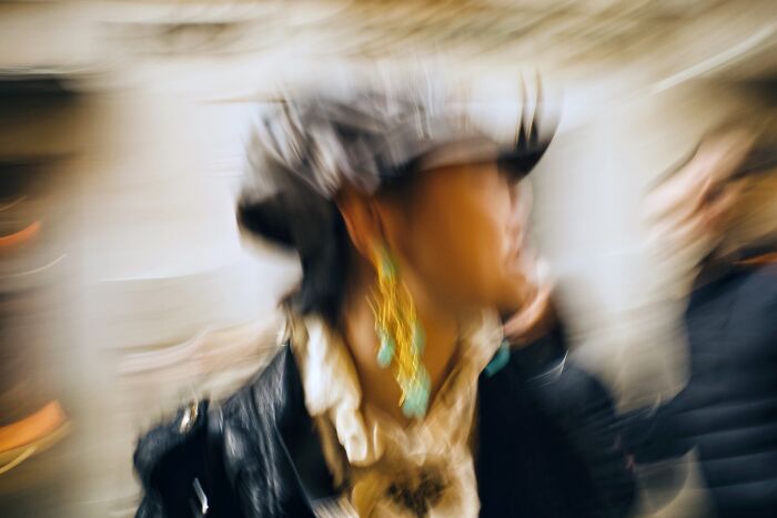 Blurred street photograph of a person wearing a hat and vibrant earrings, capturing the essence of street photography awards.