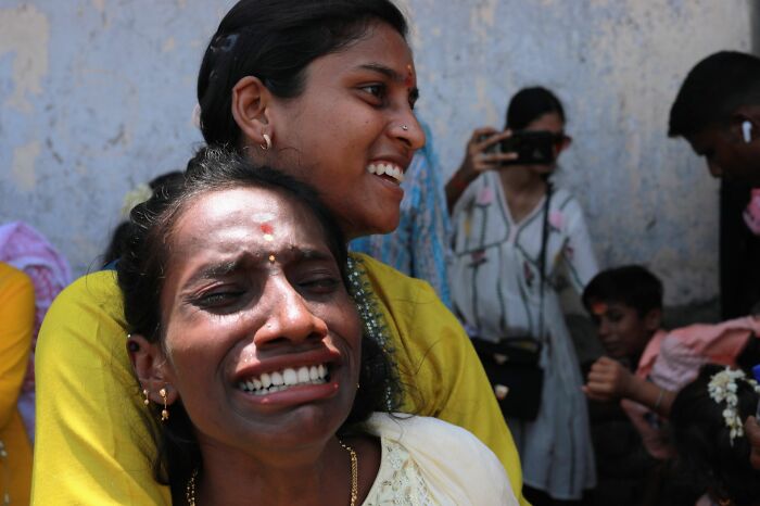 Emotional street scene showing two women, one crying and one smiling, captured in pure street photography awards style.