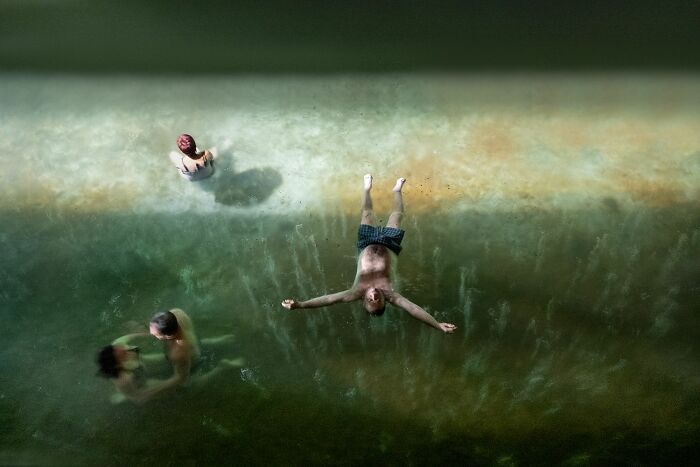 Aerial view of people swimming and floating in water, capturing candid moments in street photography awards.
