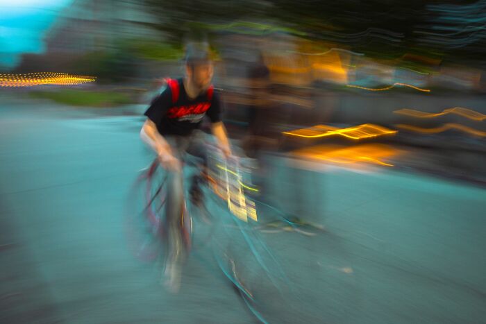 Blurred motion shot of a cyclist at dusk, showcasing dynamic energy in Pure Street Photography Awards street scenes.