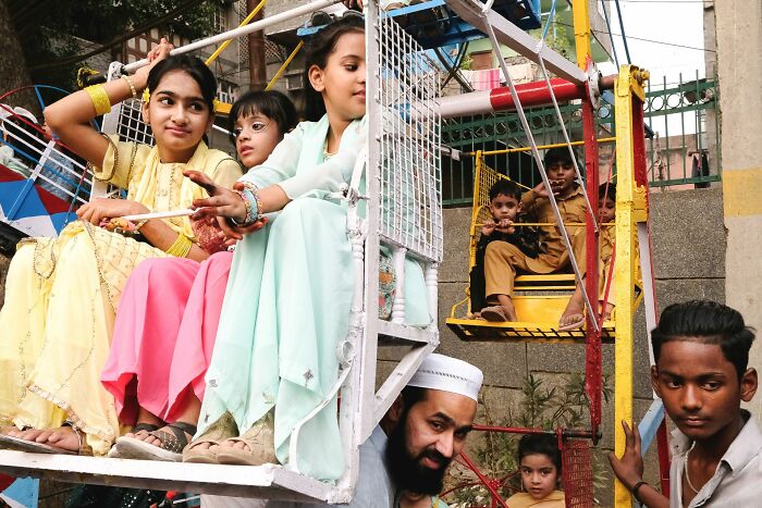 Children and adults enjoying a colorful street fair ride, capturing a vibrant moment in pure street photography awards.