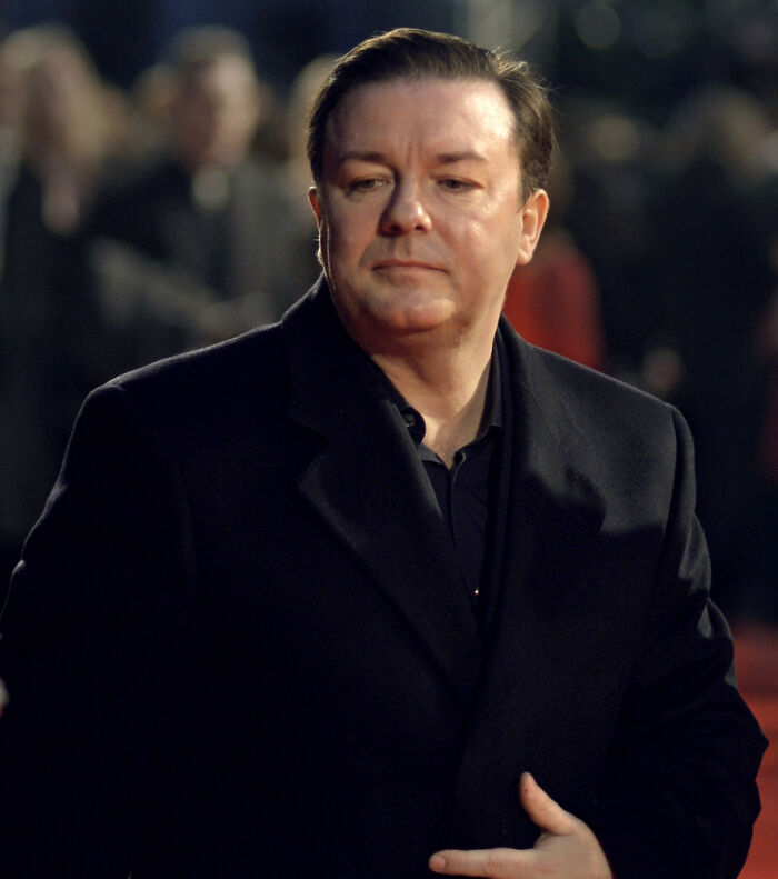 Actor in a black coat at an event, representing Hollywood stars who found fame after 30 years old.