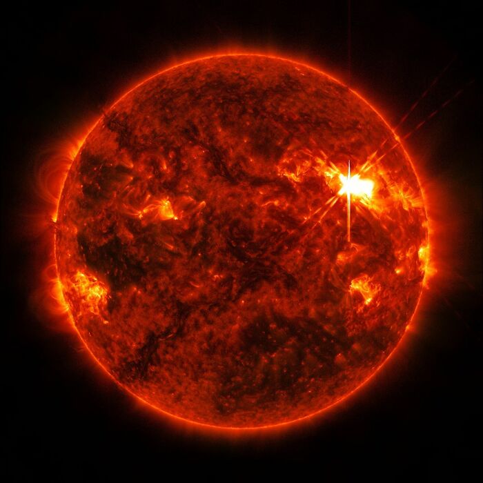 Close-up astronomy photo of the sun showcasing glowing solar flares and surface activity in vibrant orange and red hues.