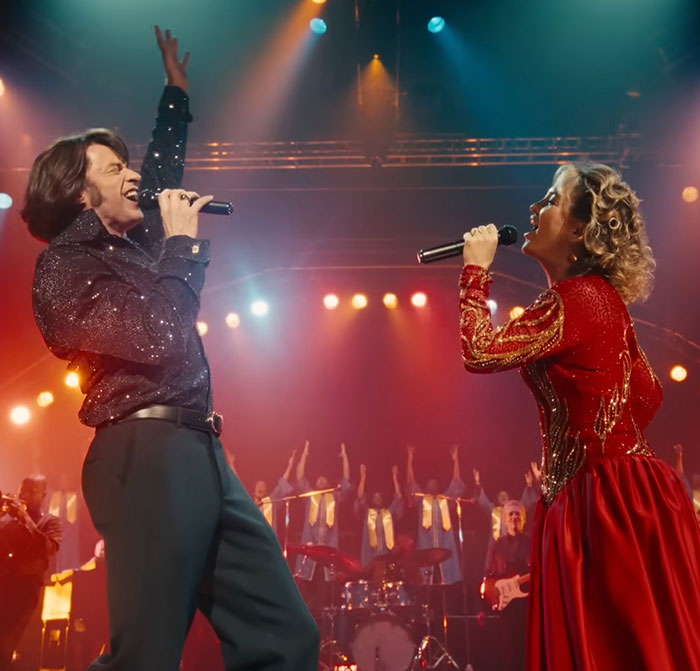 Hugh Jackman and Sutton Foster performing on stage with vibrant lighting during a lively midlife crisis themed event.