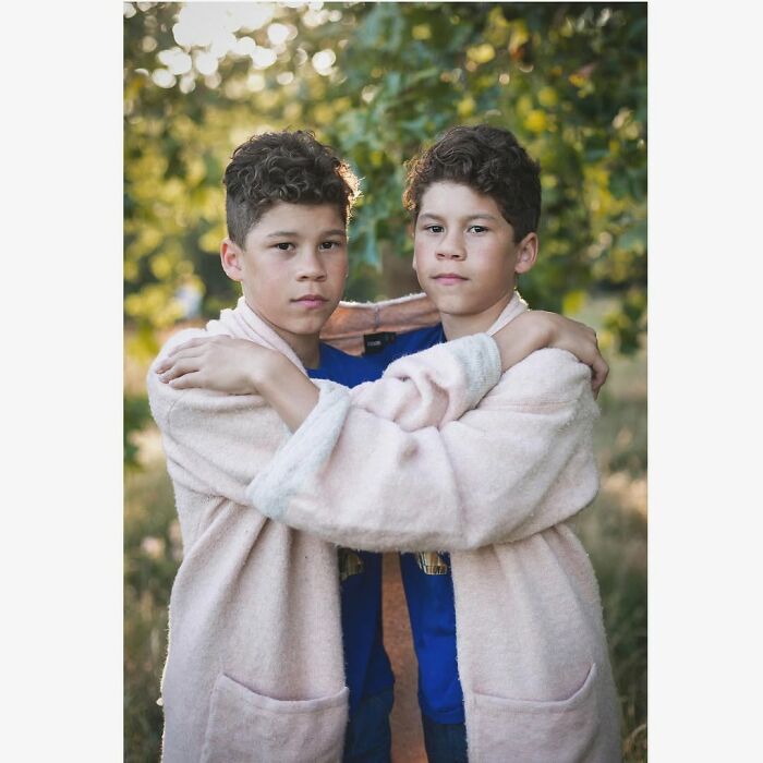 Two twin boys in matching pink robes embracing outdoors, captured by a London photographer highlighting their unique bond.