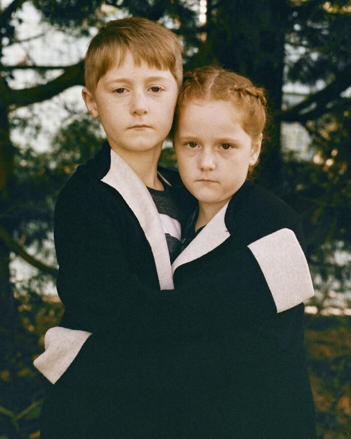 Two red-haired twins embracing outdoors, captured by a London photographer in a striking portrait showing their unique bond.