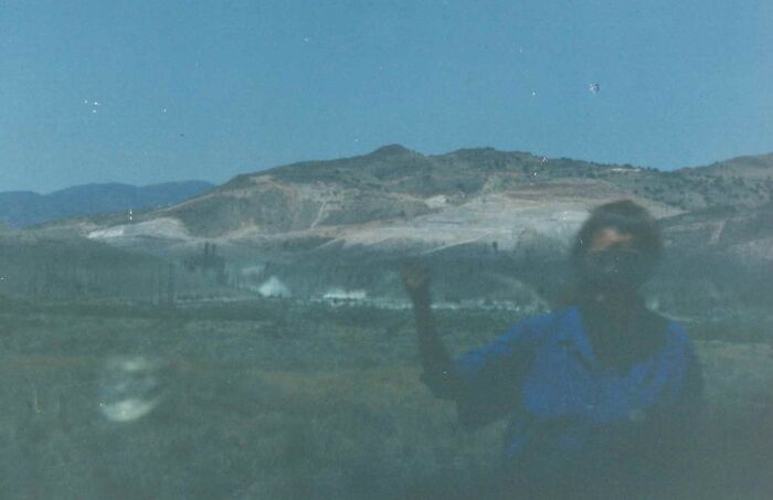 Faded photo of a person in a blue shirt with a blurry mountainous landscape, creating a creepy photo effect.