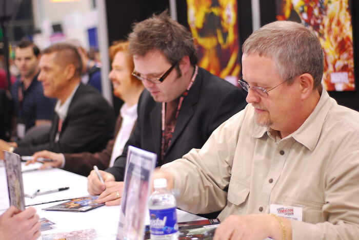 Several men at a signing event, interacting with fans in a setting showing disappointment in someone they idolized.