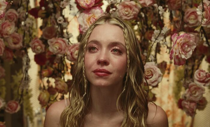 Young woman with wet hair crying, surrounded by pink roses, illustrating unrealistic women movie tropes in film scenes.