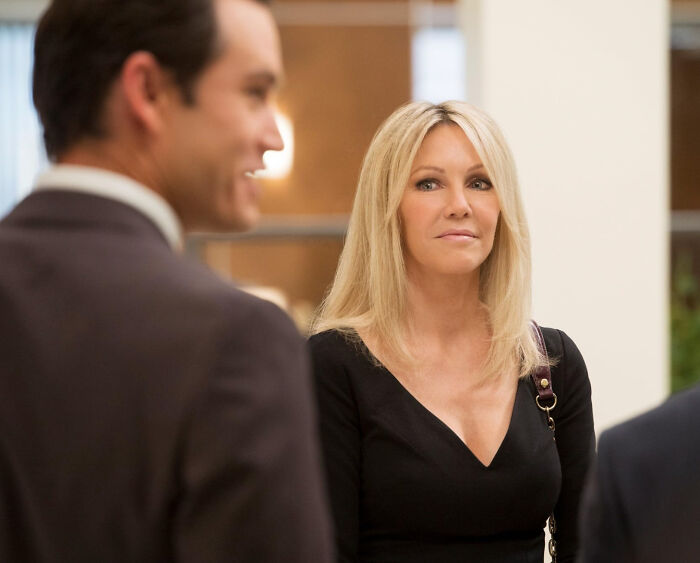 Blonde woman in black dress listening attentively during a conversation about unknown things about celebrities.