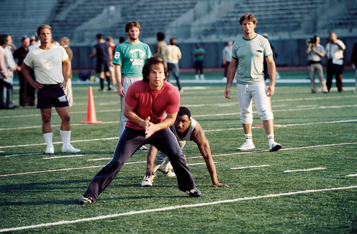 Actors rehearsing a sports scene on a football field for movies based on true stories that feel impossible to believe.