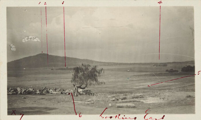 Historic view of a capital city landscape showing open fields and distant hills before modern times.