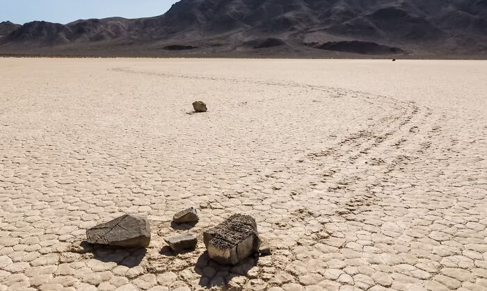 Rocks leaving trails on dry c*****d desert ground, illustrating one of the mysteries that once baffled the world solved.