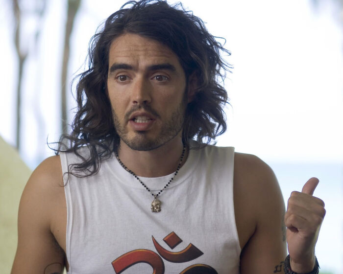 Man with long hair wearing a graphic tank top expressing disappointment, illustrating people disappointed in someone idolized.
