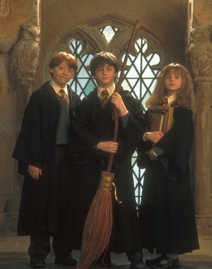 Three young wizards in robes holding a broom and books, representing disappointment in someone idolized.