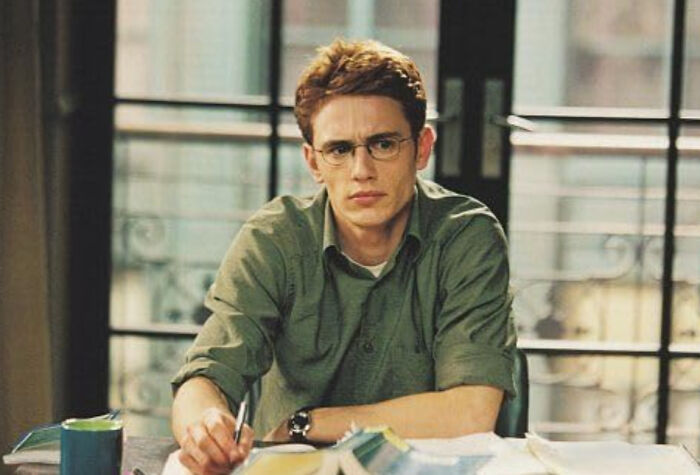 Young man looking disappointed and thoughtful while sitting at a desk with papers, illustrating disappointment in someone idolized.