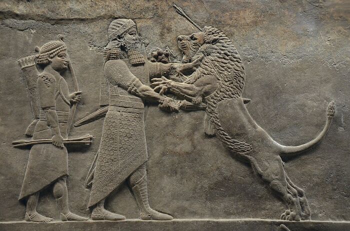Ancient stone relief showing a man confronting a lion, depicting dangerous and unsafe historical sports activities.