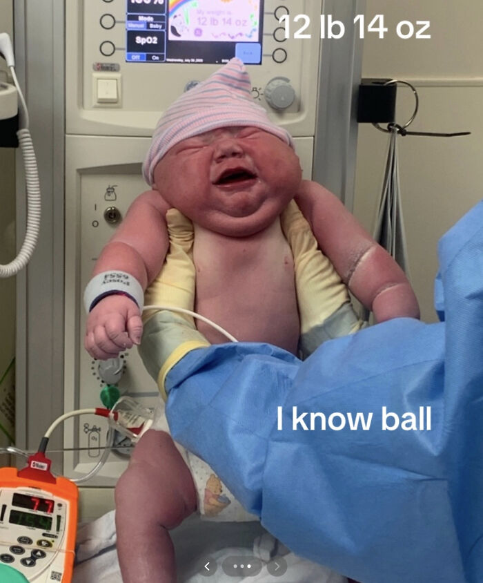 Newborn baby weighing 12 lb 14 oz held by gloved hands in hospital setting after breaking delivery record. Newborn baby weighing 12 lb 14 oz held by gloved hands in hospital setting after breaking delivery record.
