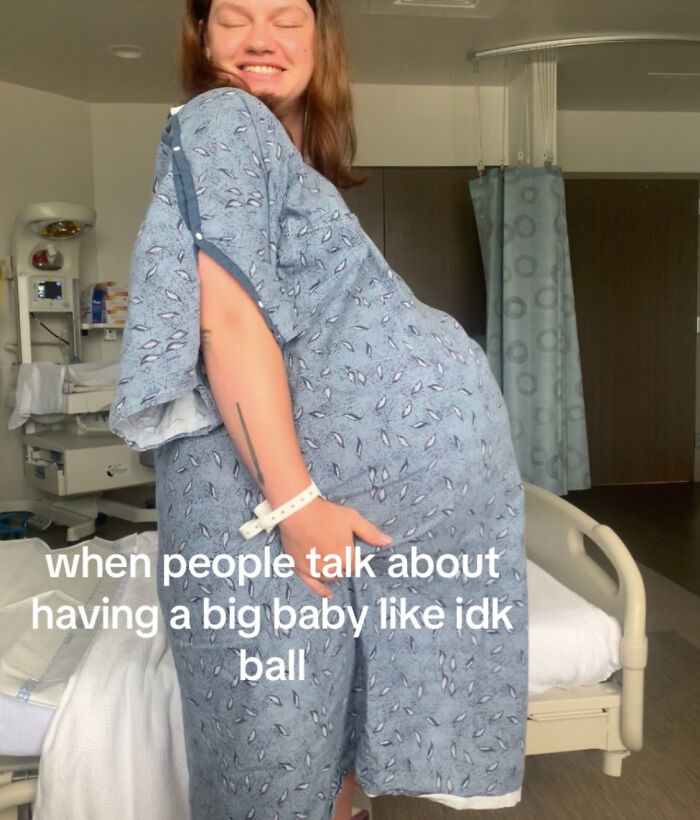 A smiling pregnant woman in hospital gown holding her large belly before delivering record-breaking big baby. A smiling pregnant woman in hospital gown holding her large belly before delivering record-breaking big baby.