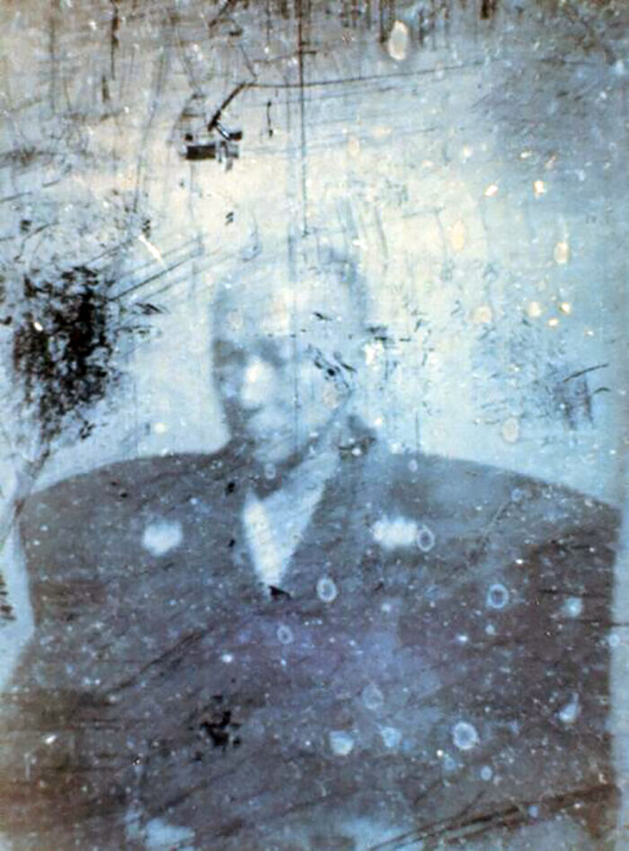 Faded and scratched early photograph of a man, showing one of the first photos from when photography was new.