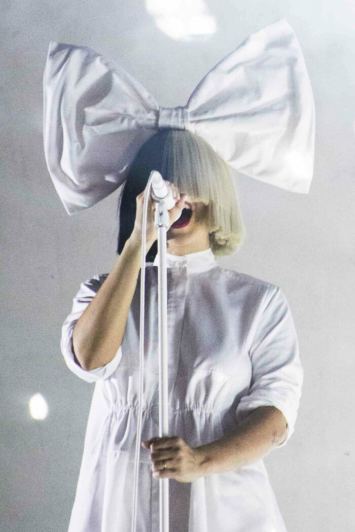 Singer with large bow headpiece performing on stage, illustrating moments people were disappointed in someone they idolized.