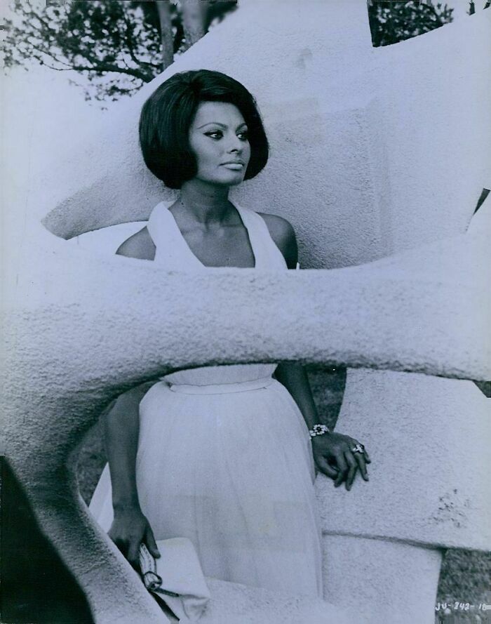 Sophia Loren posing outdoors in a white dress, showcasing classic Italian beauty and Hollywood elegance.