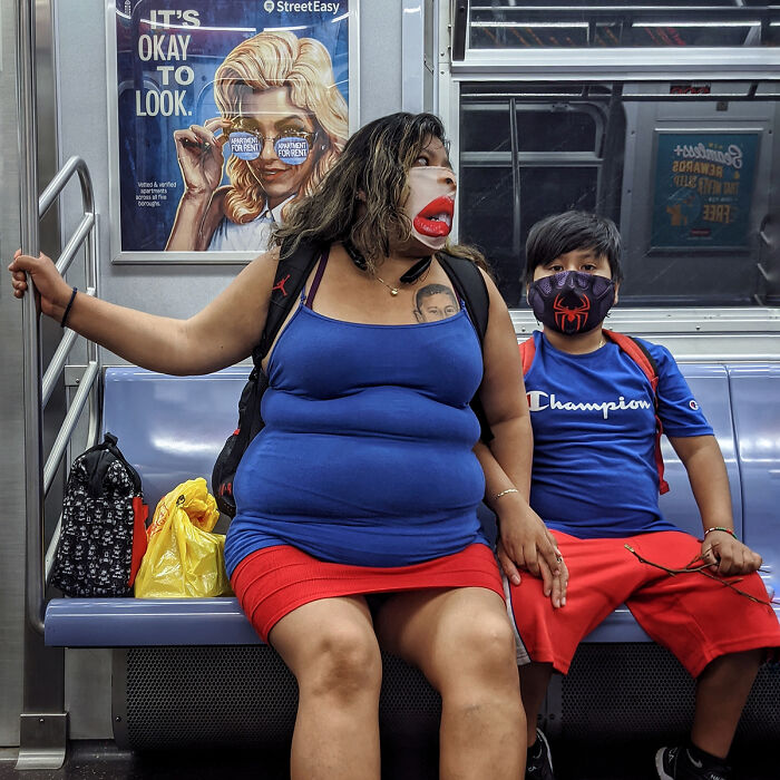 Woman and child wearing masks seated in NYC subway, captured in a candid street portrait highlighting life underground.