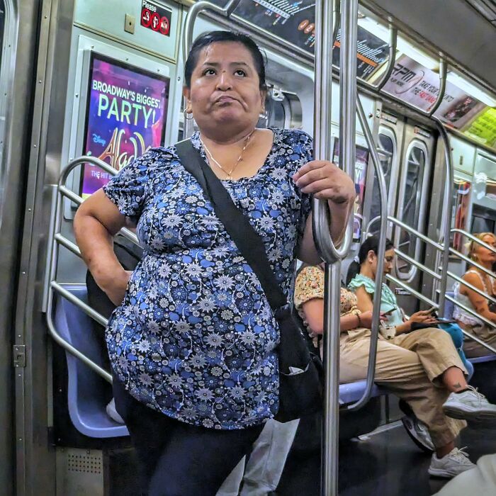 Woman in a floral top standing inside NYC subway, captured as part of street portraits showcasing life underground in the subway.
