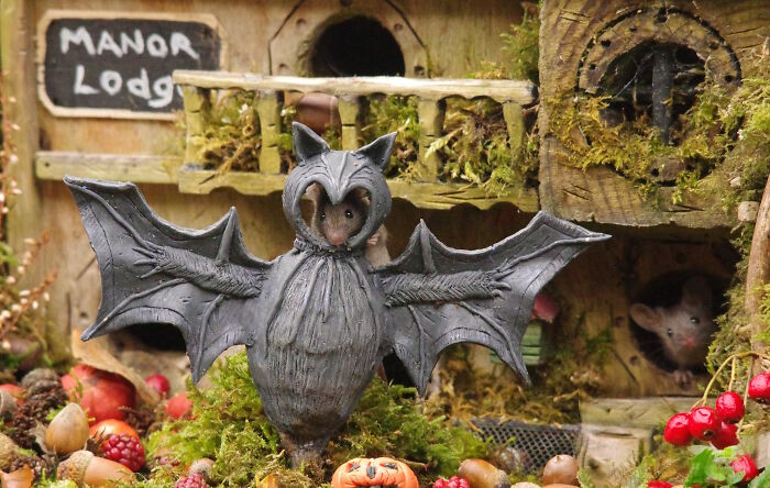 Wild mice in a Halloween village setup with a bat costume and miniature village details in a garden scene.