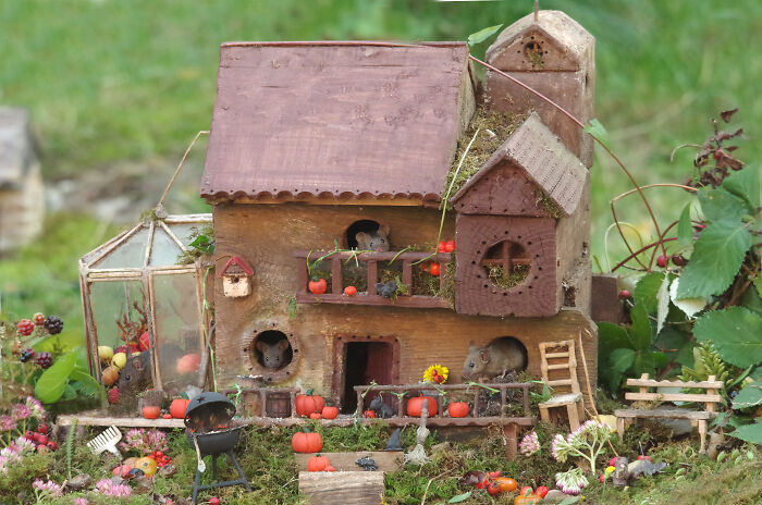 Miniature Halloween village in garden designed for wild mice with pumpkins and detailed tiny houses and decorations.