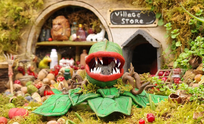 A wild mouse peeks from a Halloween village plant trap in a detailed garden setup for wild mice.