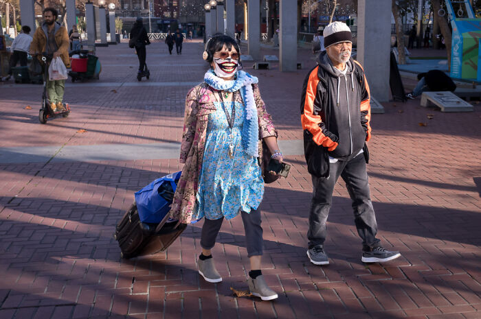 Street photographer captures humor and chaos of everyday life with candid shot of people walking in urban plaza.
